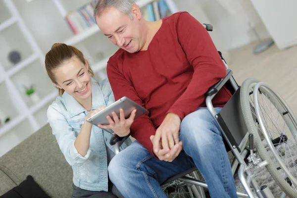 Glücklicher behinderter Mann sitzt mit Krankenschwester im Rollstuhl — Stockfoto