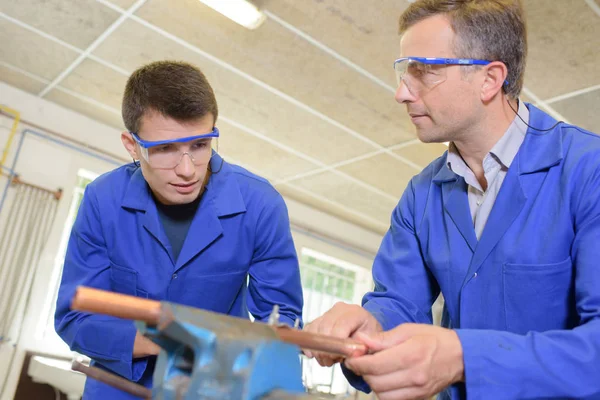 Due uomini che lavorano su tubo di rame tenuto in vizio — Foto Stock