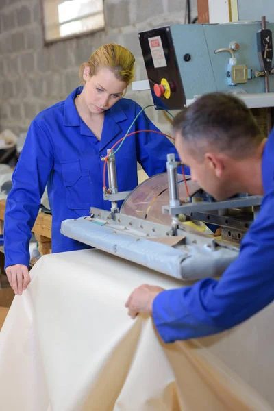 Mann und Frau bewegen Material unter Maschine — Stockfoto