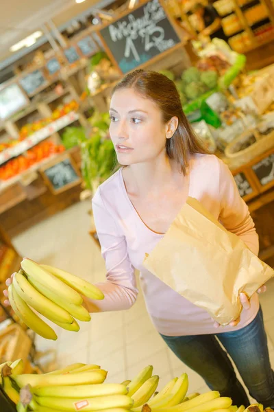 Senhora comprar bananas, segurando saco de papel — Fotografia de Stock