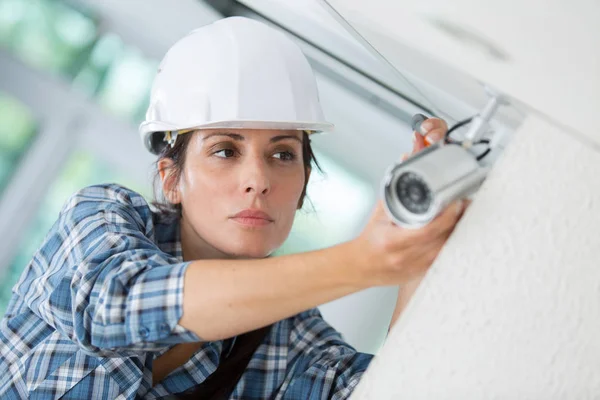 Female worker placing a security cctv camera in office building — Stock Photo, Image