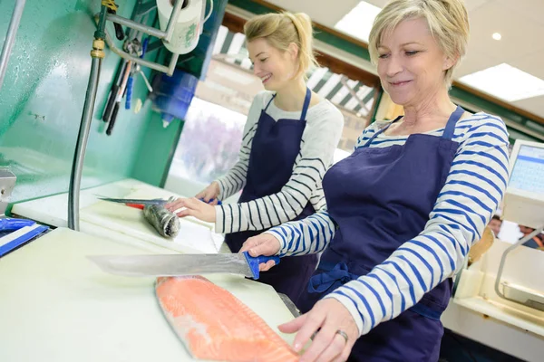 2 vrouwtjes voorbereiden van fish op vishandelaren — Stockfoto