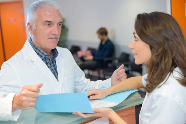 Medico e receptionist guardando i file — Foto Stock