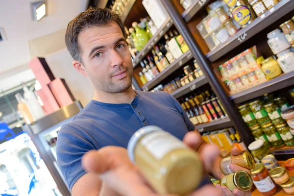 Joven mostrando artículo en delicatessen —  Fotos de Stock