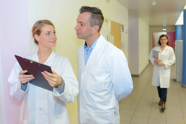 Arts kijken naar Klembord in ziekenhuis corridor — Stockfoto