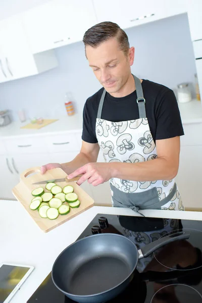 Mann legt Zucchini in die Pfanne — Stockfoto