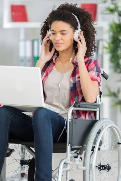 Szczęśliwa młoda dziewczyna na wózku inwalidzkim na laptopa w domu — Zdjęcie stockowe