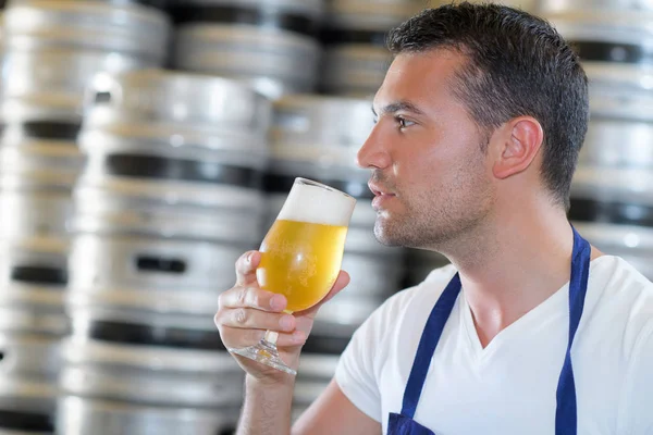 Cervejeiro bonito em cerveja de degustação uniforme na cervejaria — Fotografia de Stock