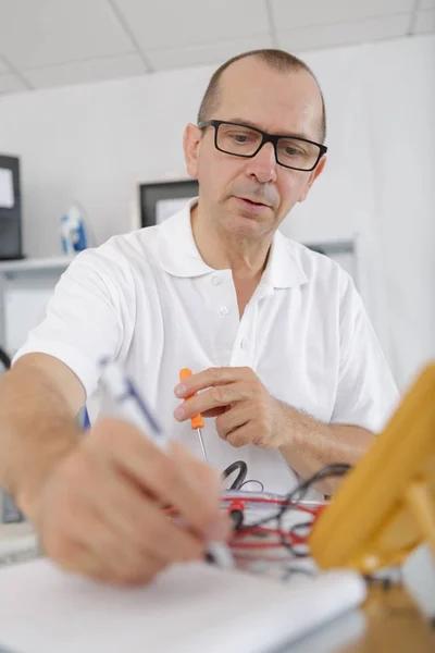 Επισκευαστής κρατώντας γυαλιά απασχολημένος στο εργαστήριό του — Φωτογραφία Αρχείου