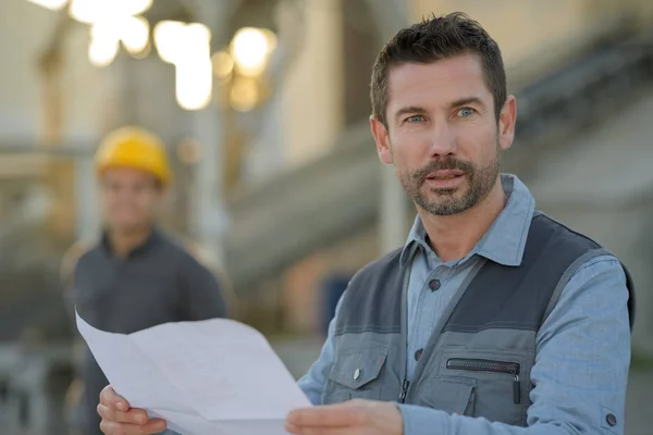 Trabajador de la construcción masculino sosteniendo un plan al aire libre del sitio de construcción — Foto de Stock