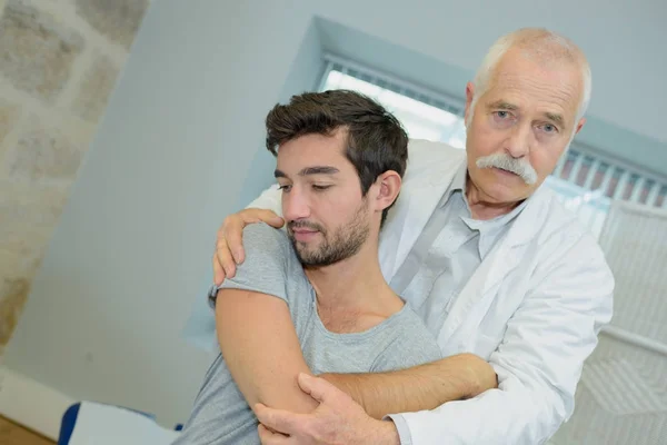 Male patient seen from behind with physio therapist — Stock Photo, Image