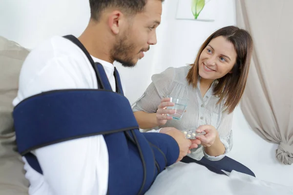 Donna che dà un bicchiere d'acqua al fidanzato ferito — Foto Stock