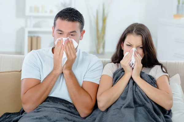 Young couple blowing their nose in tissue at home — Stock Photo, Image