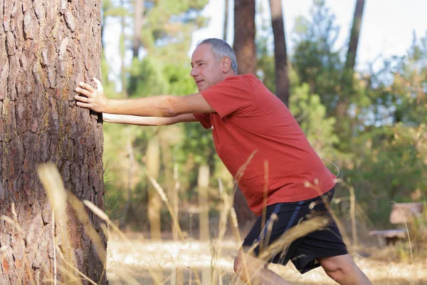 Mann breitet seine Arme auf dem Holz aus — Stockfoto