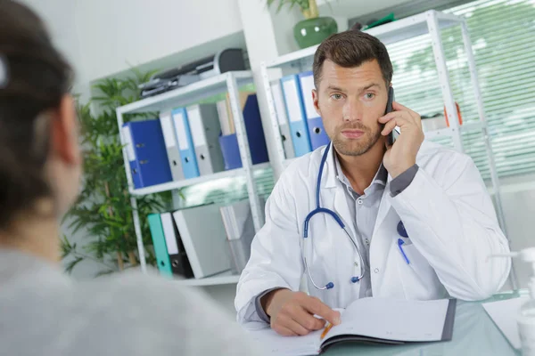 Jovem médico do sexo masculino falando ao telefone no escritório — Fotografia de Stock
