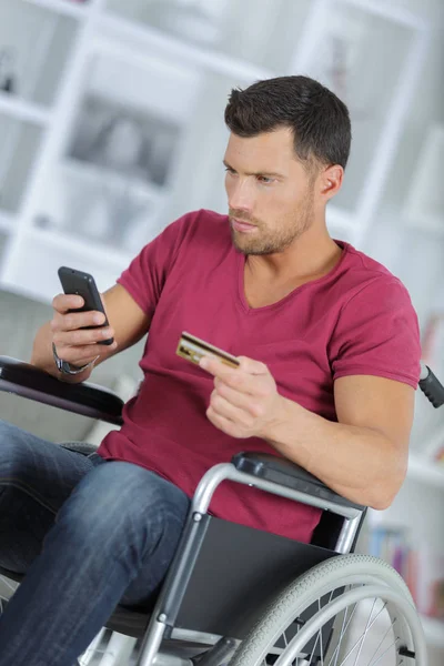 Homme en fauteuil roulant avec tablette et carte de crédit sur le lieu de travail — Photo