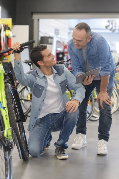 Ο άνθρωπος που γονάτισε με ποδήλατο που επιδεικνύεται οθόνη tablet από δεύτερο άτομο — Φωτογραφία Αρχείου
