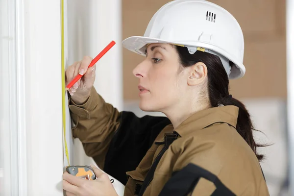 Low angle shot of female carpenter working with spirit level — Stock Photo, Image