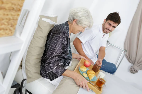 Krankenschwester serviert Seniorin zu Hause das Frühstück — Stockfoto