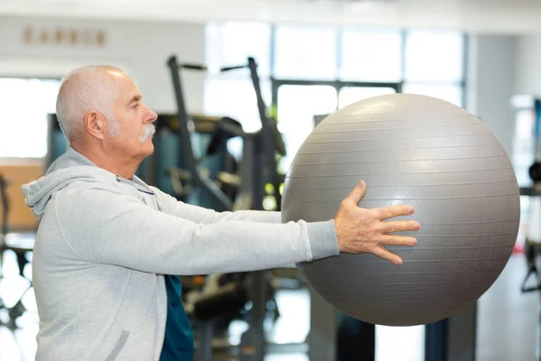 Homem idoso ativo segurando uma bola de fitness — Fotografia de Stock