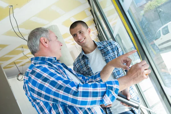 Två byggare arbetstagare installera glasfönster — Stockfoto