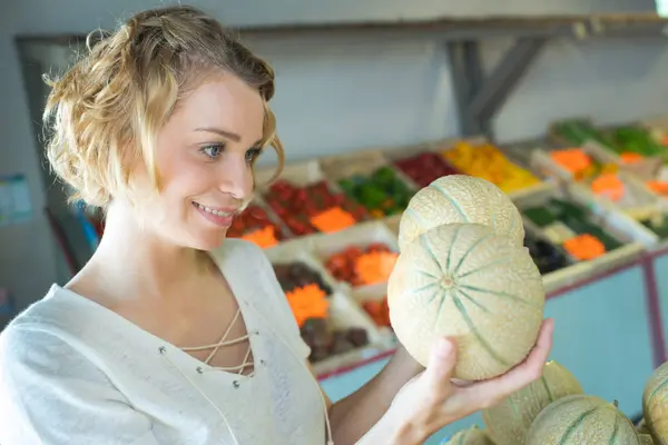 Schöne Frau wählt reife Bio-Melone — Stockfoto