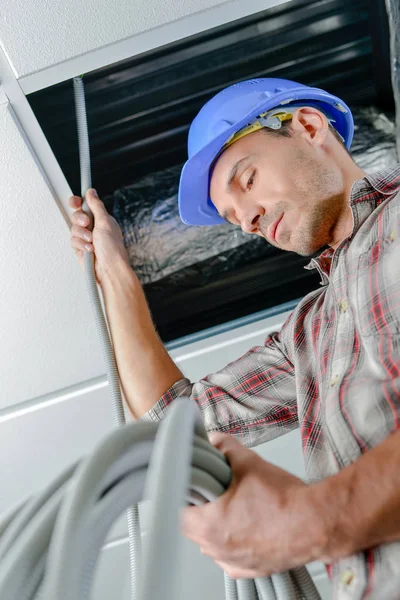 Man voeding kabel boven verlaagde plafond — Stockfoto