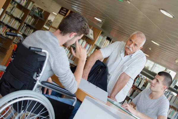 Insegnante aiutare gli studenti in biblioteca — Foto Stock