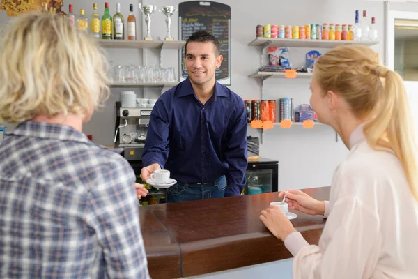 Två kvinnliga vänner flirta med en stilig bartender — Stockfoto