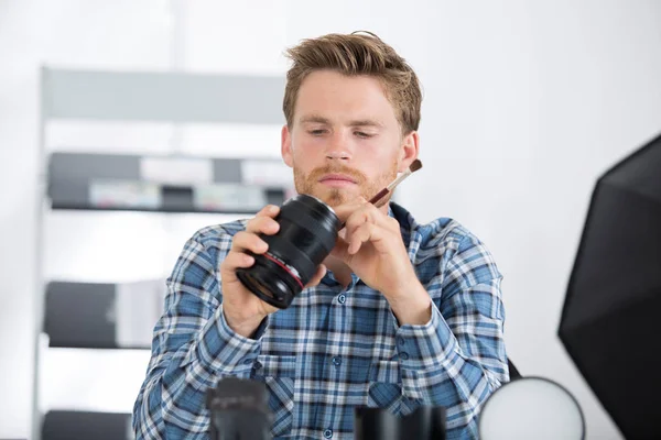 Homem inspecionando a lente da câmera — Fotografia de Stock