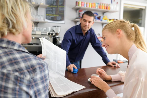 Vriend controleren nieuws in de krant op koffie plaatsen — Stockfoto