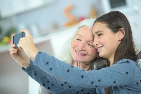 Menina e avó tirando fotografia com celular — Fotografia de Stock