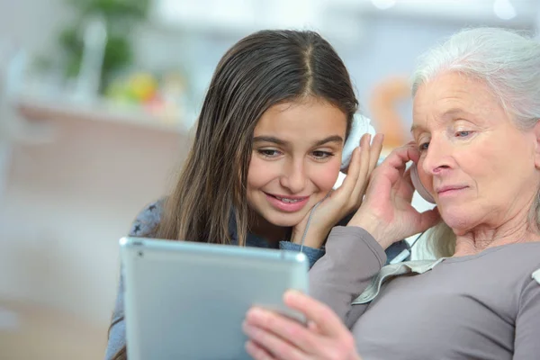 Счастливая внучка и бабушка играют с планшетом — стоковое фото