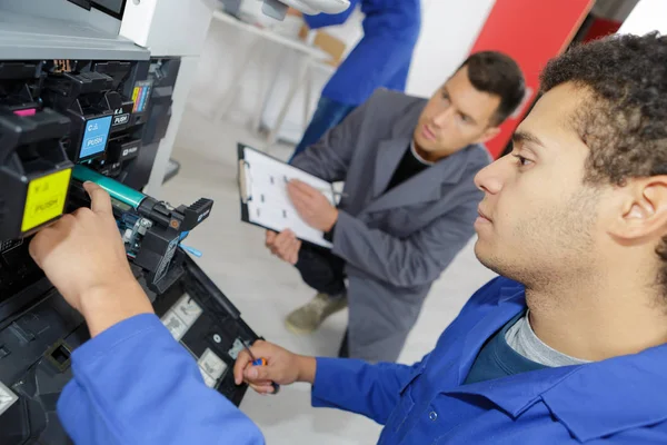 Jovem técnico do sexo masculino reparando máquina fotocopiadora digital — Fotografia de Stock