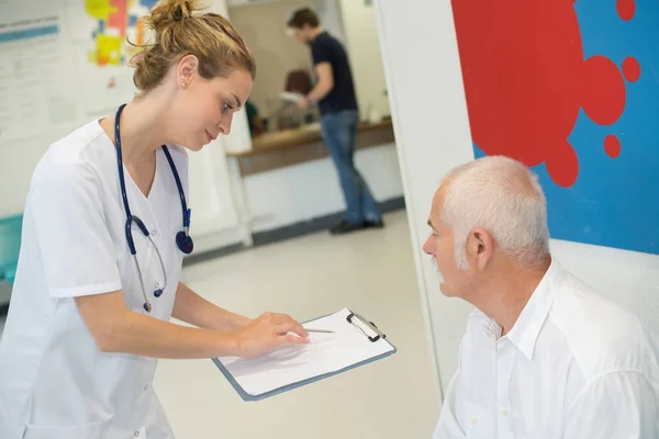 Médico e paciente discutindo sobre relatório na sala de espera do hospital — Fotografia de Stock