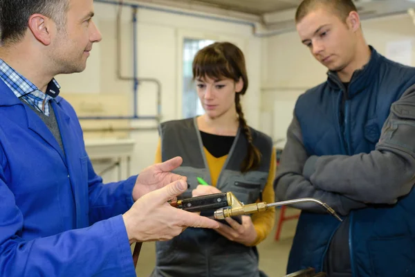 Insegnante di ferriere che mostra agli studenti come utilizzare saldatore a gas in modo sicuro — Foto Stock