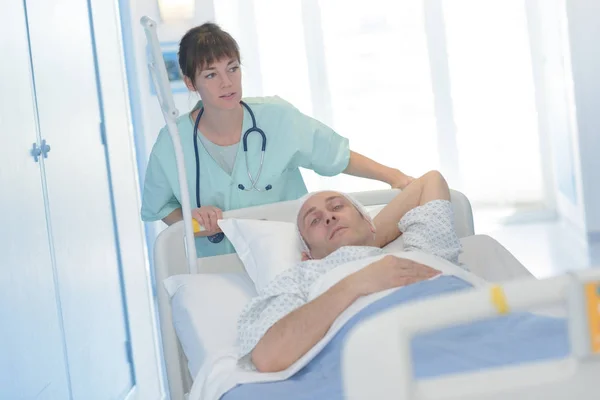 Médico bonito transportando um paciente deitado em uma maca — Fotografia de Stock