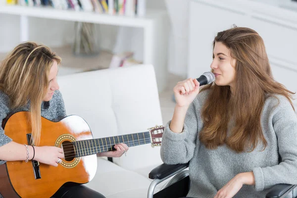 Młodych kobiet gry na gitarze podczas przyjaciel wózek inwalidzki, śpiew — Zdjęcie stockowe