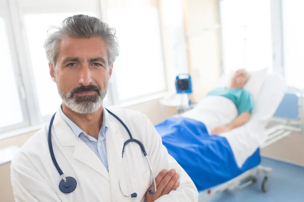 Retrato del médico con paciente en cama en segundo plano —  Fotos de Stock