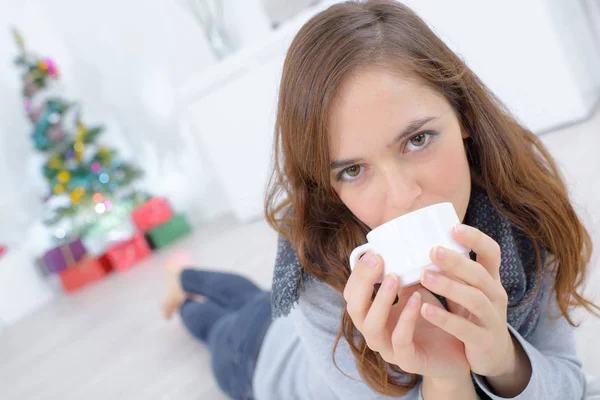 Portret van de vrouw gelegd op verdieping houdt een kopje — Stockfoto