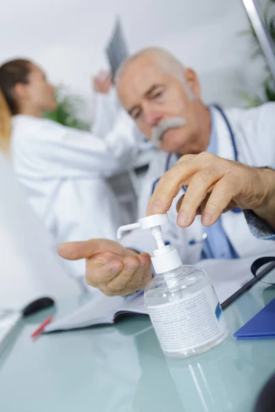 Médico dispensando desinfetante na mão — Fotografia de Stock