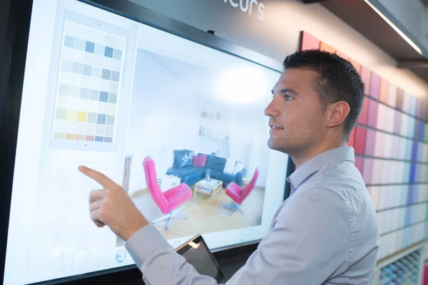 Joven guapo interactuando con la pantalla táctil en la tienda — Foto de Stock