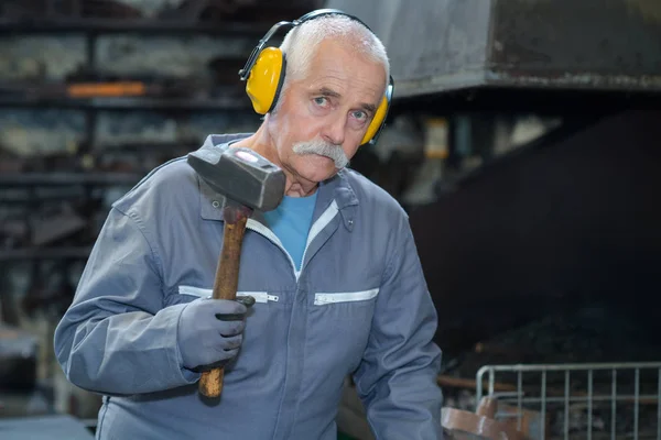 Erfahrener Schmied mit Hammer in seiner Werkstatt — Stockfoto