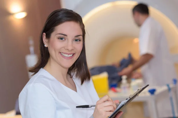 Doctor leyendo portapapeles con colega preparando paciente para ct — Foto de Stock