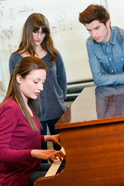 Um professor de música com dois alunos durante a aula de piano — Fotografia de Stock