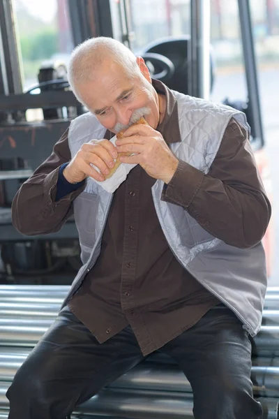 Trabalhador comendo um pão — Fotografia de Stock