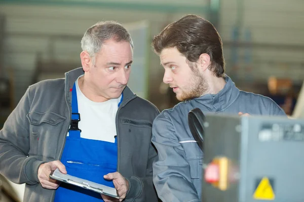 Fiatal mérnök tárgyal mentorával a gyárban — Stock Fotó
