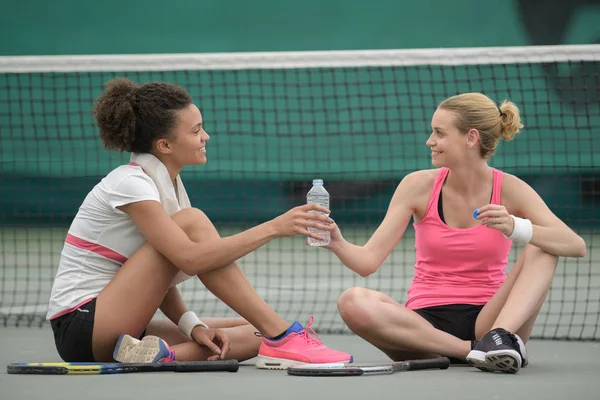 Donne che condividono una bottiglia d'acqua sul campo da tennis — Foto Stock