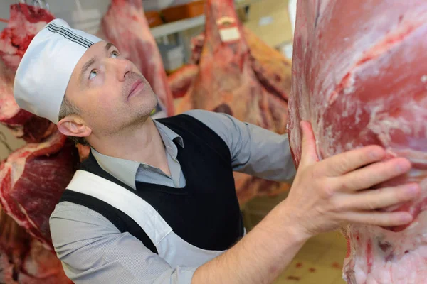 Slaktaren holding sida av nötkött — Stockfoto