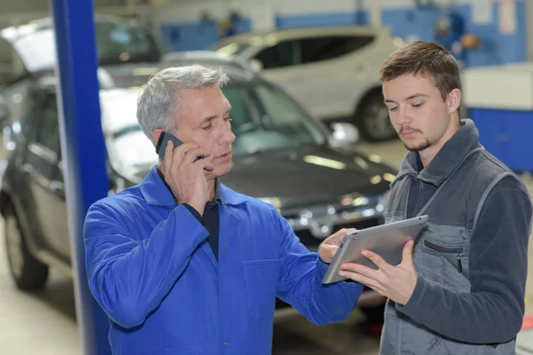 Estudante com instrutor reparar um carro durante a aprendizagem — Fotografia de Stock